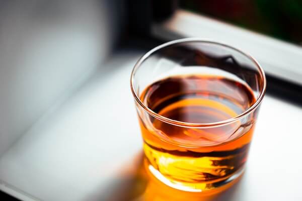 透明なグラスの中で光る琥珀色のウイスキー