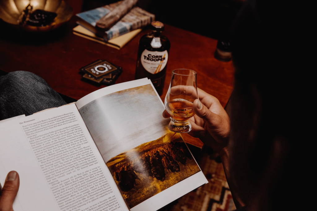 ウイスキーを飲みながら本を読む男性