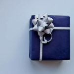 青い包装紙にシルバーのリボンをかけたプレゼントの画像